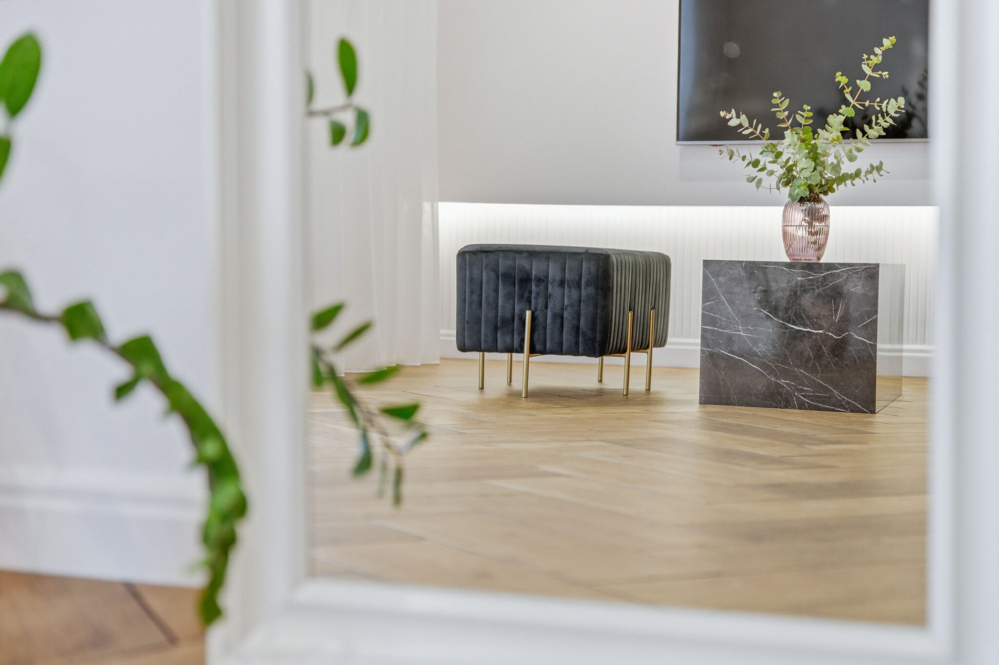 Moderný interiér bytu s elegantným taburetom a mramorovým stolíkom