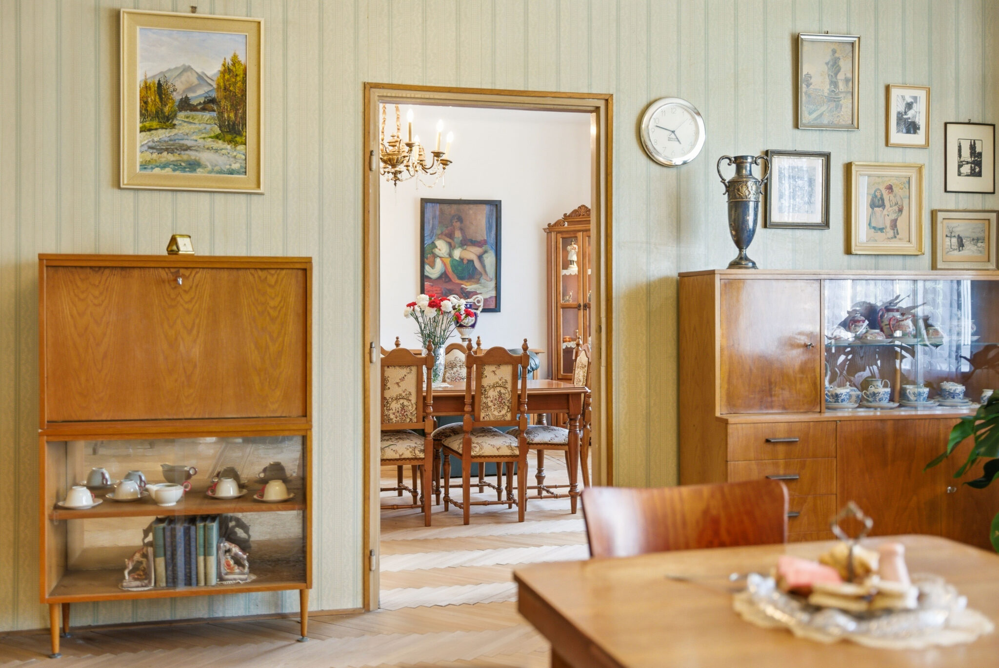Retro interiér bytu s dreveným nábytkom, obrazmi a výhľadom do jedálne